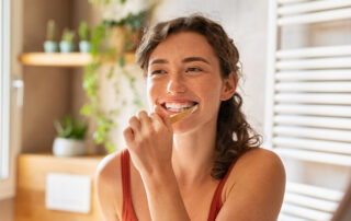 Woman Brushing her teeth in front of a mirror - Proper Brushing and Flossing Techniques