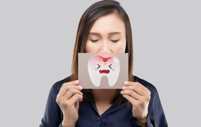 Woman holding a cartoon tooth with a painful expression, symbolizing a sensitive tooth. Ideal visual for understanding how to stop teeth sensitivity and explore sensitive teeth prevention. Brighter Smiles Family Dentistry helps patients with sensitive teeth in West Des Moines